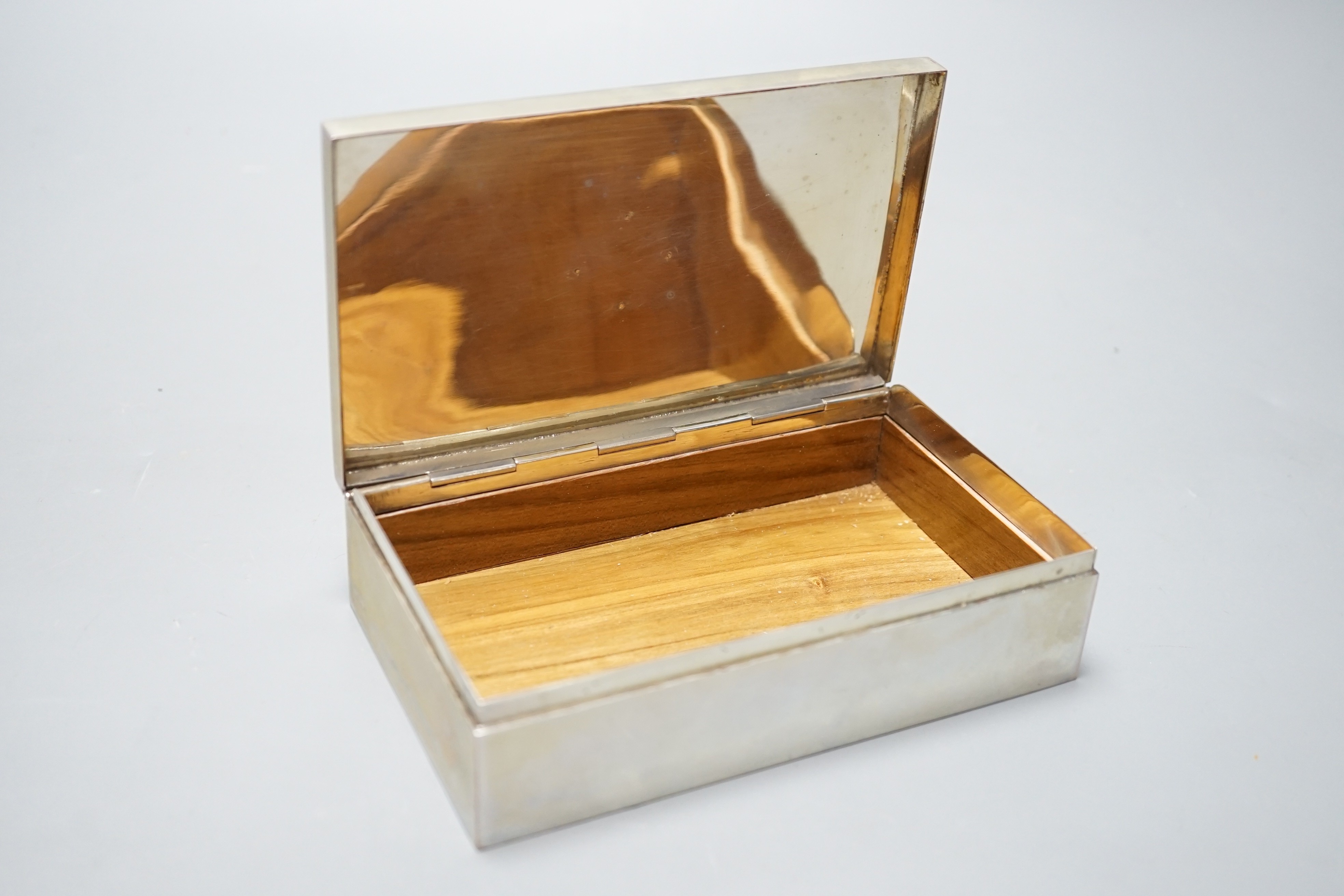 A white metal rectangular cigarette box, with yellow metal appliqué, 15.1cm, gross 15.1oz.